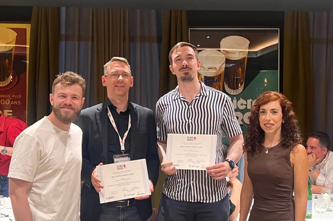Preisverleihung der ICWE 2026 in Lyon: zwei der Ausgezeichneten halten die Best-Student-Paper-Urkunden in die Kamera